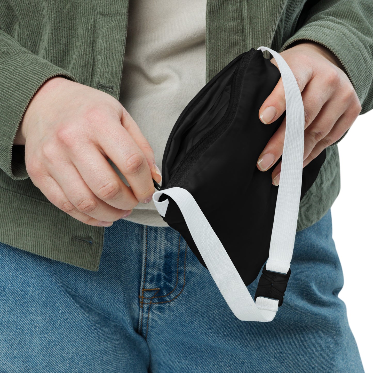 Person holding a black waist bag with a white strap